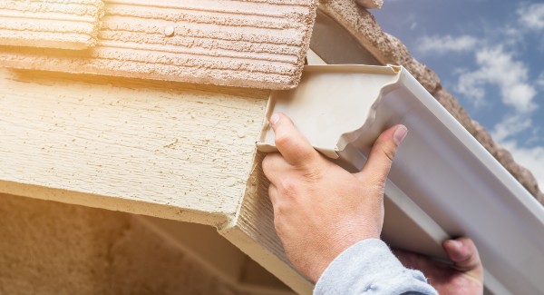 Man installing a new gutter on house